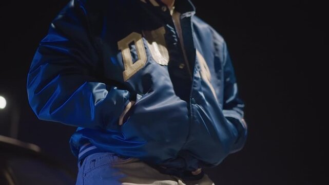 Caucasian male inspecting pockets at night, Man positioning his jacket under city lights with confident stance, Young white male adjusting his coat at night while checking pockets in urban glow
