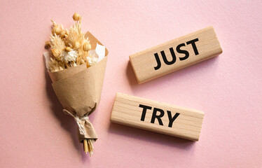 Just try symbol. Concept words Just try on wooden blocks. Beautiful pink background with bouquet of flowers. Business and Just Try concept. Copy space.