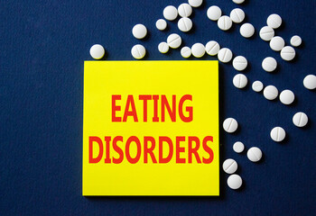 Eating Disorders symbol. Concept word Eating Disorders on yellow note. Beautiful deep blue background with pills. Medicine and Eating Disorders concept. Copy space