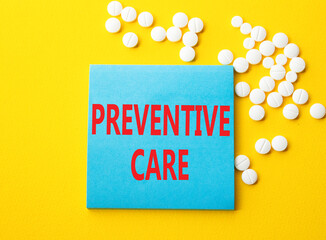 Preventive Care symbol. Concept word Preventive Care on blue note. Beautiful yellow background with pills. Medicine and Preventive Care concept. Copy space
