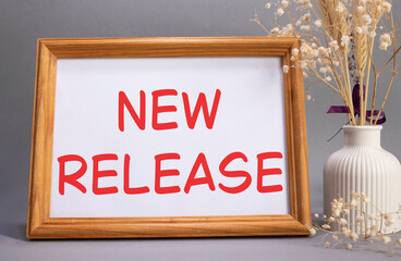 New Release symbol. Concept words New Release on beautiful wooden picture frame. Beautiful grey background with flower vase. Business and New Release concept. Copy space.