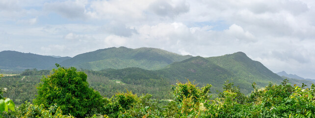 Scenic panoramic view of green mountains and tropical forests under cloudy sky natural landscape of...