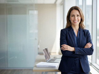 Beautiful hispanic senior business woman with crossed arms smiling at camera. European or latin confident mature middle age leader female businesswoman standing at office workplace, copy space. 