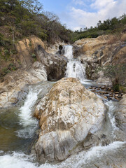Water falls over rocks in a natural landscape near a river stream