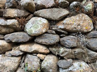 Old stone wall built of various sizes of rocks in a rural area
