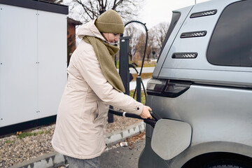 Confident transition unfolds as a adult female plugs in her electric car at a public charger,...