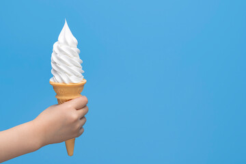 青背景に手に持つバニラソフトクリームコーンとコピースペース