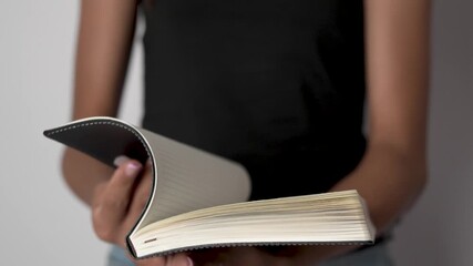 Hands opening a black paper notebook or diary, close up.