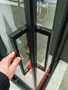 secure office entry featuring metal handle and reflective glass surroundings, access to contemporary office space through manual door handle with reflective glass facade and security measures