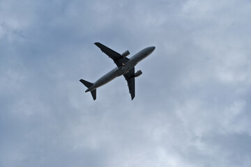 Fototapeta premium Airplane in the cloudy sky. White Plane Climbing Through Clouds Half a Minute Post-Takeoff.