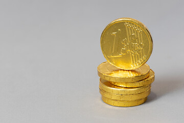 Pile of chocolate Euro coins isolated on gray background with copy space
