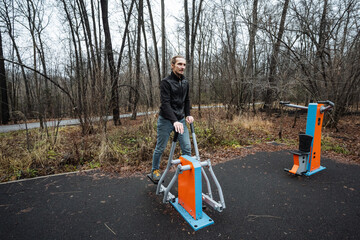 urban gym session, person boosts energy by exercising outdoors in urban park setting, individual enhances wellbeing with evening outdoor workout amidst damp leaves and cloudy skies