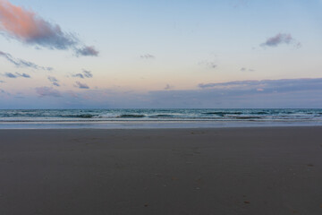 Serene Sunset Over Calm Ocean Waves at Sandy Beach Shoreline