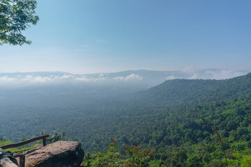 Vast Green Landscape with Misty Mountains Under Clear Blue Sky