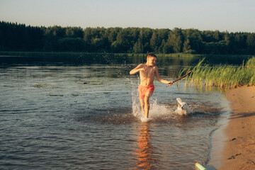 Young Boy and Dog Playing with Stick in the Water