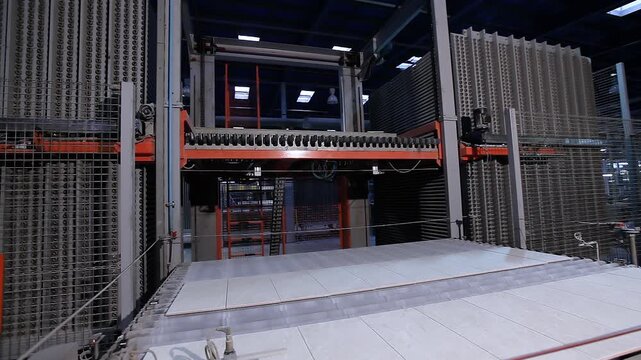 The process of making ceramic tiles. Ceramic tile manufacturing plant. A production line or conveyor belt at a ceramic and porcelain tile factory. Close-up of ceramic tiles being loaded for firing.