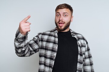 Fototapeta premium Man wearing a plaid shirt raises his hand while smiling against a plain background in a casual setting
