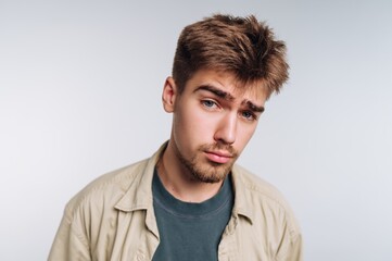 Obraz premium Young man with short hair and beard poses against a plain background in a casual setting during the daytime