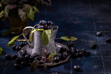 Blueberries overflowing from rustic tin cup on dark background