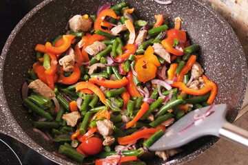 Closeup side view of meat being moved around a heated wok with a silicone spatula, demonstrating proper stir fry technique and pan control for online culinary courses and educational videos