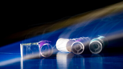 pequeñas bobinas de hilo de varios colores sobre fondo azul y negro dejando una estela © Ramón Reyes