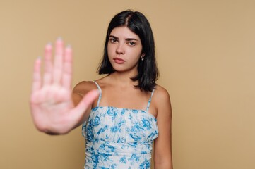 Obraz premium Young woman shows hand indicating stop against a neutral background during a casual indoor setting