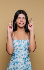 Fototapeta premium Young woman hopes for good luck with crossed fingers in indoor setting