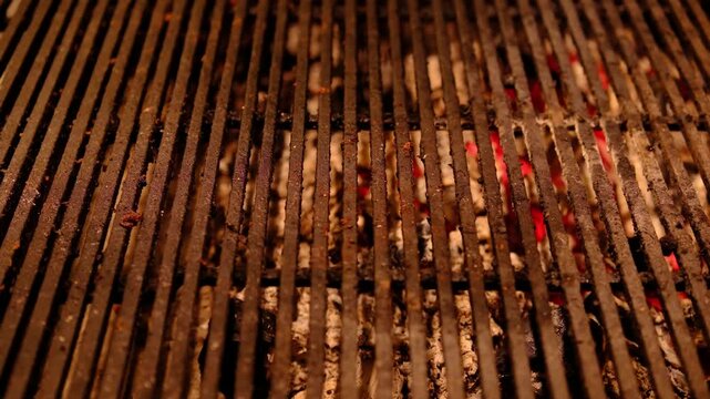 Warm dark metal barbecue grill grate with hot glowing red embers for slow outdoor cooking