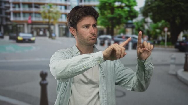Young hispanic man with raised hands palm out on city street signaling stop to oncoming traffic and pedestrians; caution personal boundary.