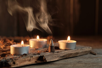Three Candles and Incense Burning on Wooden Surface in a Dim Space