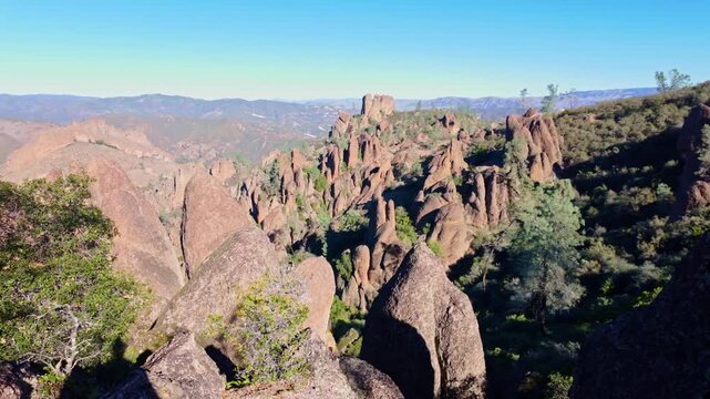 Jagged volcanic rock formations and towering spires of the High Peaks rising sharply against the sky along a Pinnacles hiking trail