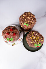 Panettone with a melted chocolate topping and cherries, peanuts, and pistachios_top view_vertical.