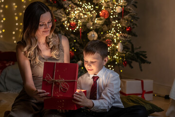 A young woman and her son open a Christmas present. Mary Christmas concept