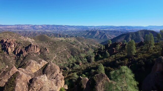 Jagged volcanic rock formations and towering spires of the High Peaks rising sharply against the sky along a Pinnacles hiking trail