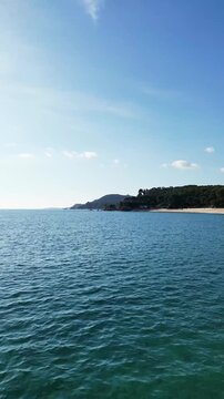Aerial drone view, flying at the Spanish coastline with empty beach, mountains, blue sea and sky, Lloret de Mar, vertical nature background	