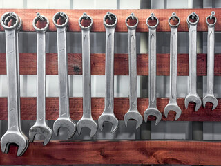 Wrench tool set with metal spanners hanging in garage workshop, organized mechanic equipment for repair, service and maintenance in industrial or DIY workspace.