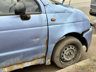 Decrepit Rusty Vehicle Exhibiting Corrosion And Multiple Surface Damages In Condition, Weathered And Corroded Car With Dents And Surface Deterioration Revealing Extensive Damage