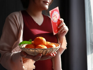 Lunar new year, An Asian woman wearing a red shirt is carrying a basket of mandarin orange for symbolizes good luck and wealth