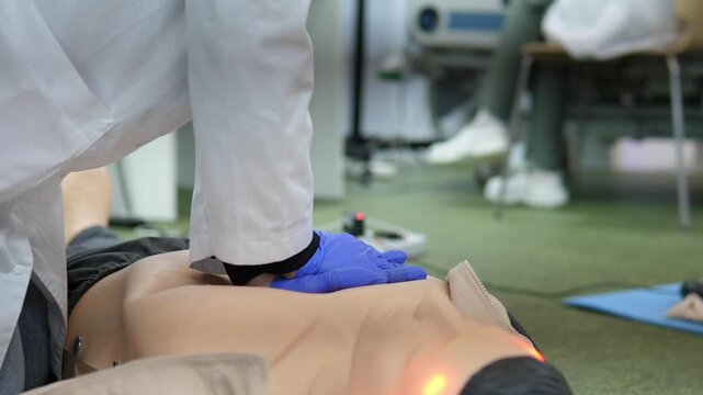 paramedic using bag valve mask during compressions on mannequin with gloved hands dynamic classroom simulation shows coordinated bagging and chest compressions, audible metronome