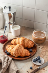 Delicious breakfast with croissants on wooden tray and coffee on white kitchen table background