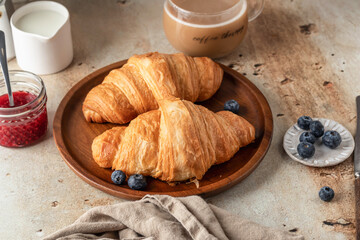 Delicious breakfast with croissants on wooden tray and coffee on white kitchen table background