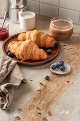 Delicious breakfast with croissants on wooden tray and coffee on white kitchen table background, text space