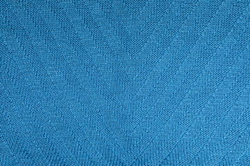 Seamless close-up of a handmade knitted blue background with an elegant herringbone pattern. Suitable as a background for fashion, knitting, winter clothing, and handmade craftsmanship.