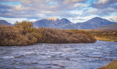 Wide tundra landscape with river and mountains in Rondane