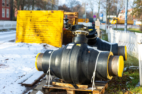 Insulated heating pipeline valves pallets urban site during winter energy maintenance utility. District heating equipment shows steel pipes, safety control technology public utility supply Germany