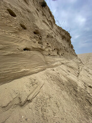 eroded sand cliff with horizontal layers and sky