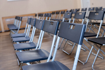 folding black chairs stand in a row on a white wooden floor outside