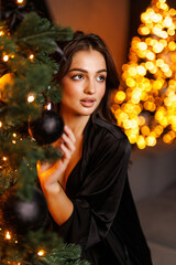 young woman celebrates Christmas standing near tree. new year meets and waits for miracles.