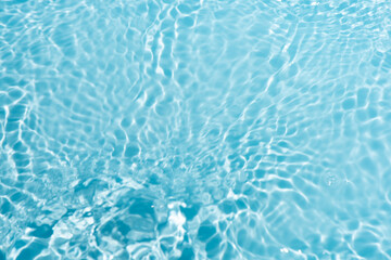 Blue water with ripples on the surface. Defocus blurred transparent blue colored clear calm water surface texture with splashes and bubbles. Water waves with shining pattern texture background.
