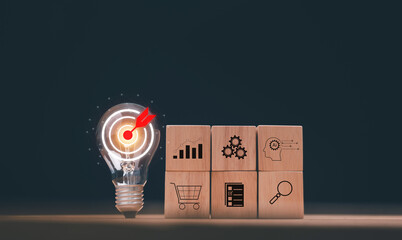 Business target achievement concept. Light bulb with target icon and marketing symbols on wood cubes. Smart planning, innovation, AI thinking, analytics and e-commerce solution for modern business.